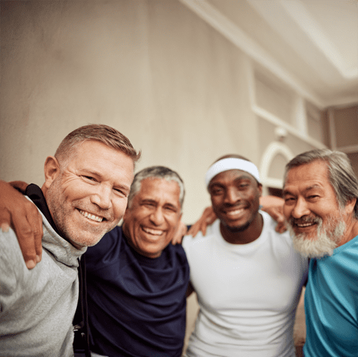ll-men-image Four diverse men smiling with arms around each other in athletic wear, showing friendship and camaraderie